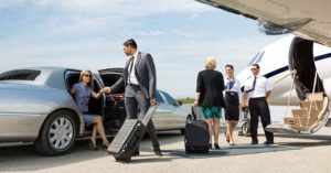 Business partners about to board private jet while airhostess and pilot greeting them